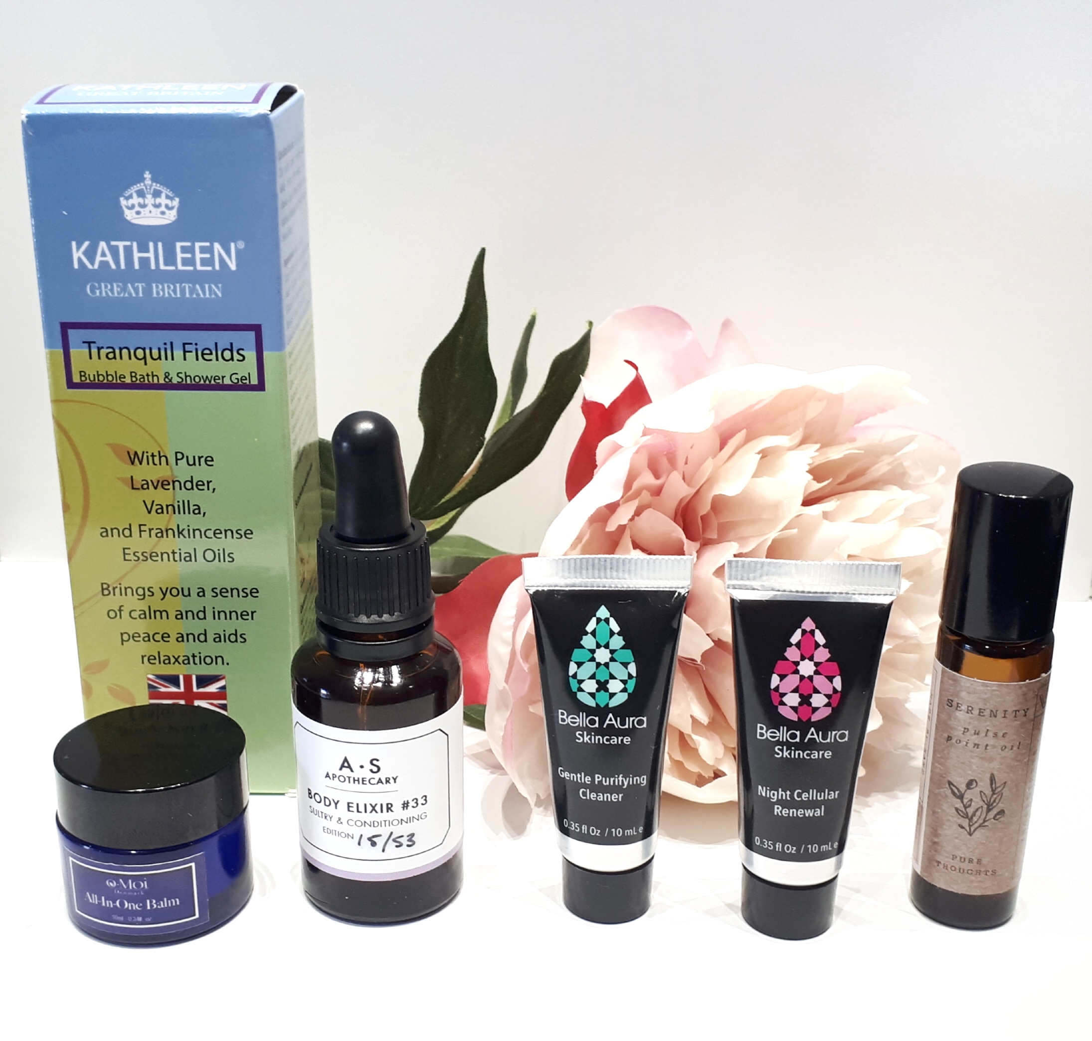 All six products stand in a line in front of a pink flower on a white background.