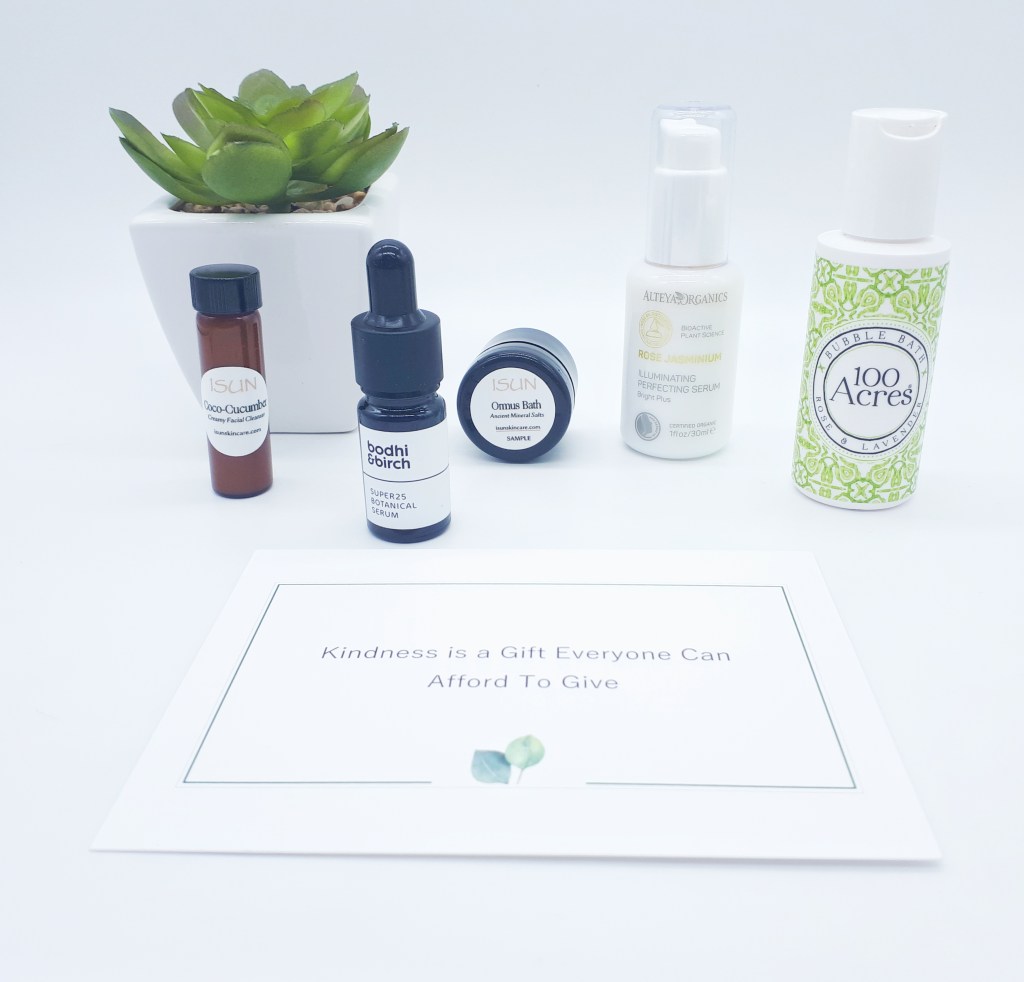All the products are lined up on a white background. On the left, slightly behind the products is a green plant in a white square pot.