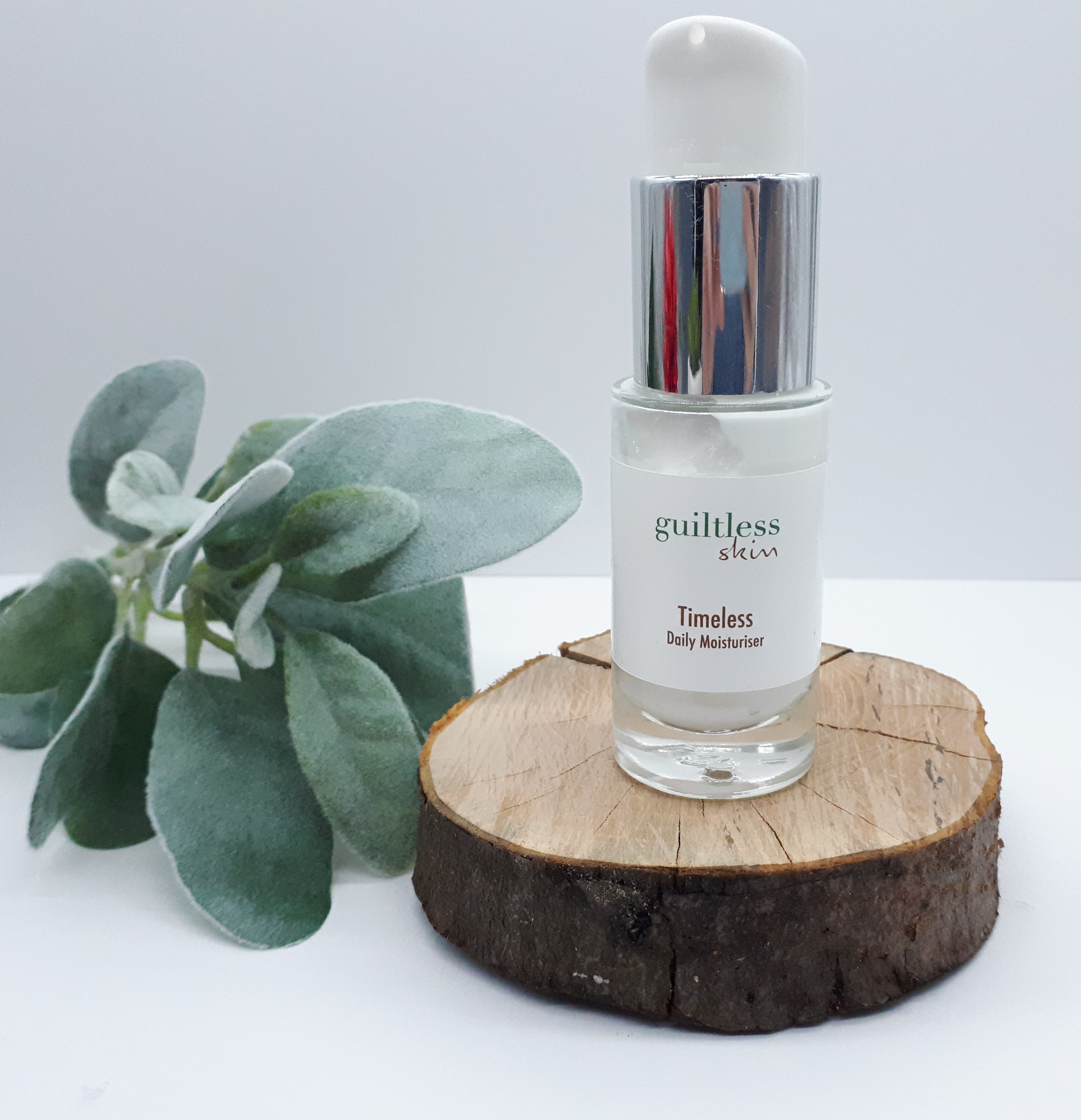 Timeless Moisturiser standing on a log slice with frosted foliage to the side