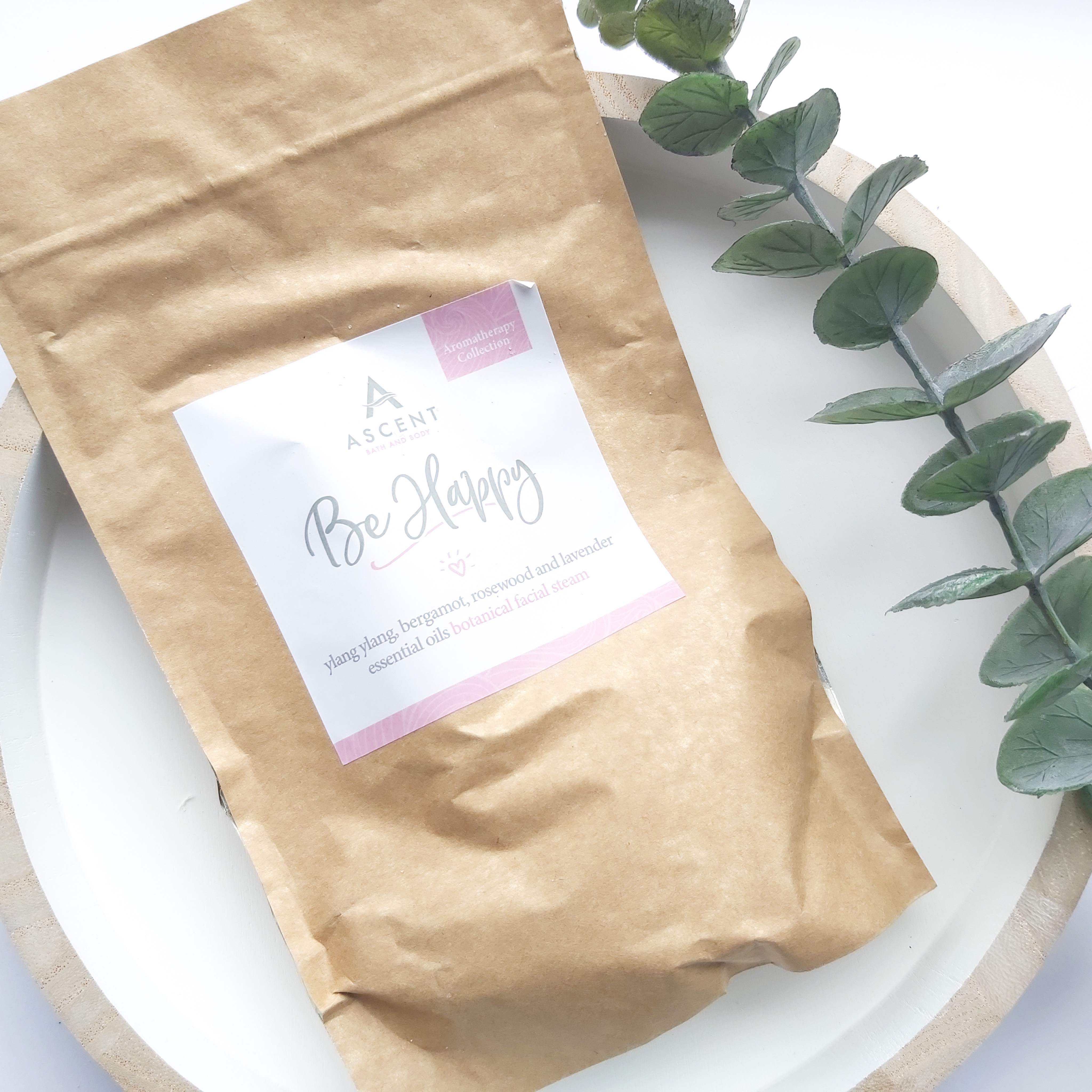 A brown pouch of facial steam sits on a white, wooden round tray with a eucalyptus stem to the side - Freedm Street Subscription Beauty Box review by Beauty Folio