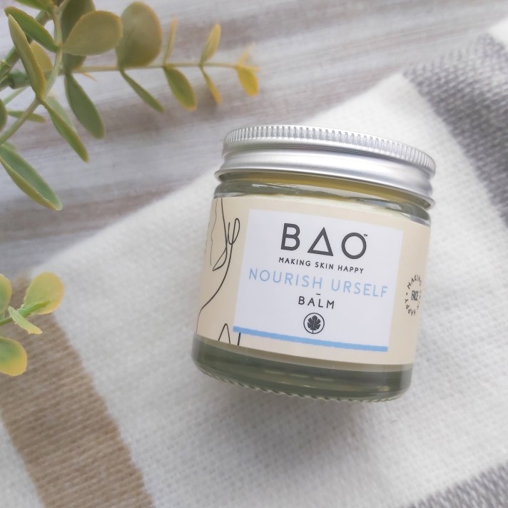 Bao Skincare Nourish Urself Balm on a check blanket with green eucalyptus foliage and wooden tray. Green Beauty Guide - Kind Origins Review by Beauty Folio.