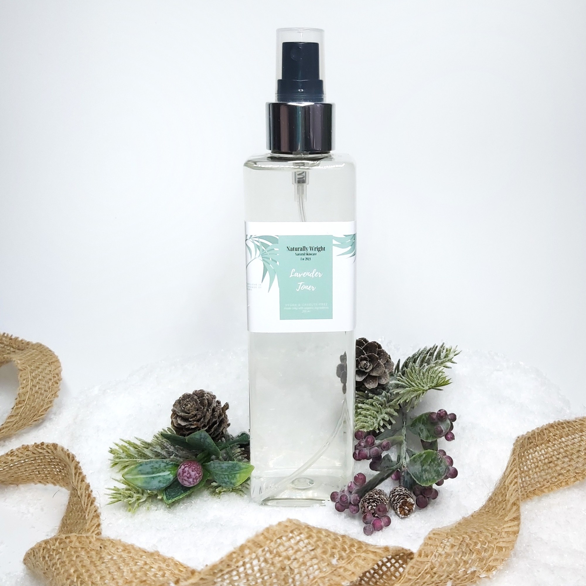 Naturally Wright Lavender Face Toner in a clar bottle, sat on snow with Christmas foliage and jute ribbon.Christmas foliage. Natural Beauty Christmas Gift Guide by Beauty Folio.