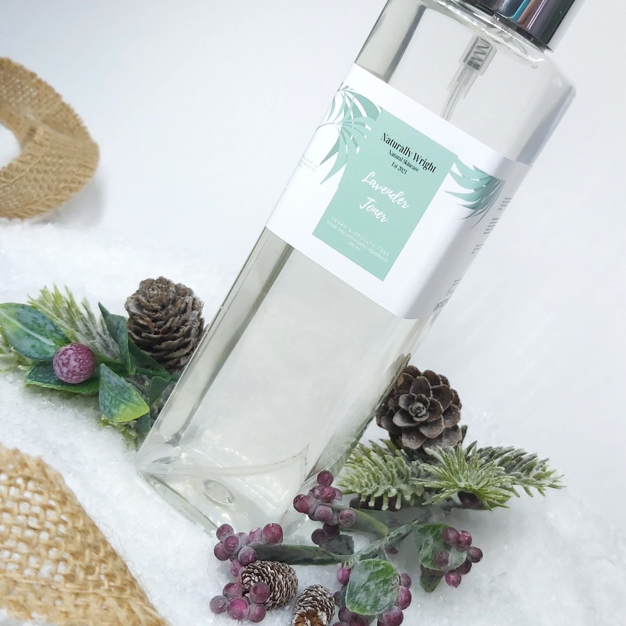 Naturally Wright Lavender Face Toner in a clar bottle, sat on snow with Christmas foliage and jute ribbon.Christmas foliage. Natural Beauty Christmas Gift Guide by Beauty Folio.
