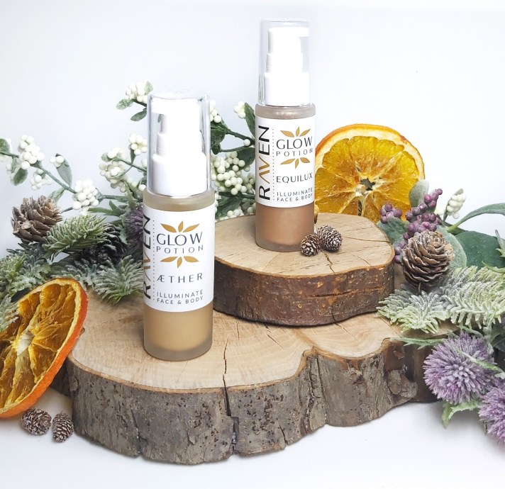 Raven Botanicals Glow Potions Aether and Equilux bottles stand on wooden log slices with christmas foliage and orange slices. Natural Beauty Christmas Gift Guide by Beauty Folio