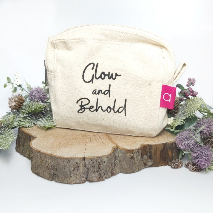 Amaranthine Skincare's Minis Bundle branded cosmetic bag on a log slice with festive foliage. Natural Beauty Christmas Gift Guide by Beauty Folio.