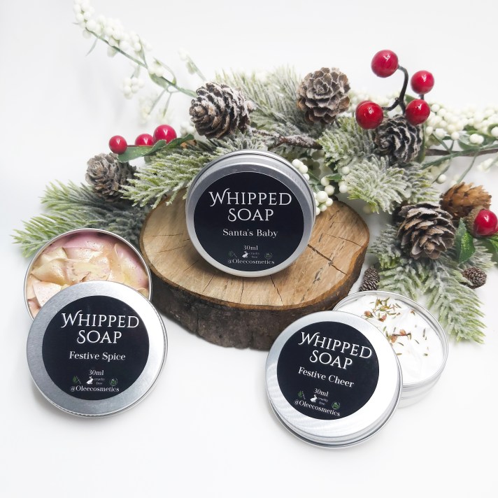 Olee Cosmetic Mini Whipped Soaps on a log slice with Christmas foliage. Natural Beauty Christmas Gift Guide by Beauty Folio.