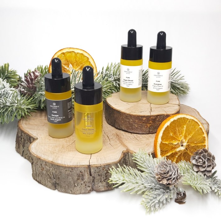 Organic Youth Discovery set bottles standing on a log slice with Christmas foliage and orange slices. Natural Beauty Christmas Gift Guide by Beauty Folio.