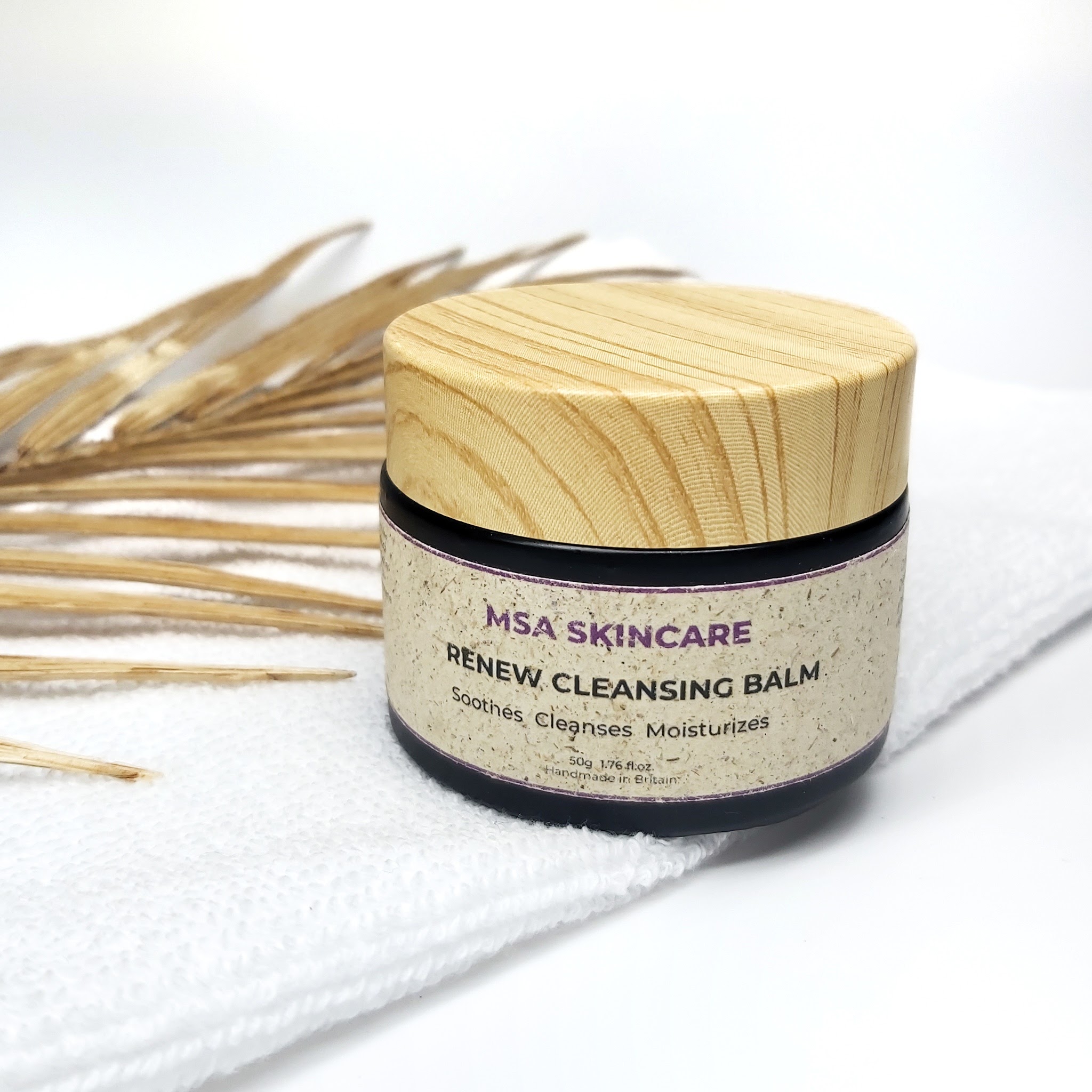 MSA Skincare Cleansing Balm with a white background, sitting on top of a white towel with a natural palm leaf in the background. Natural skincare review by Beauty Folio