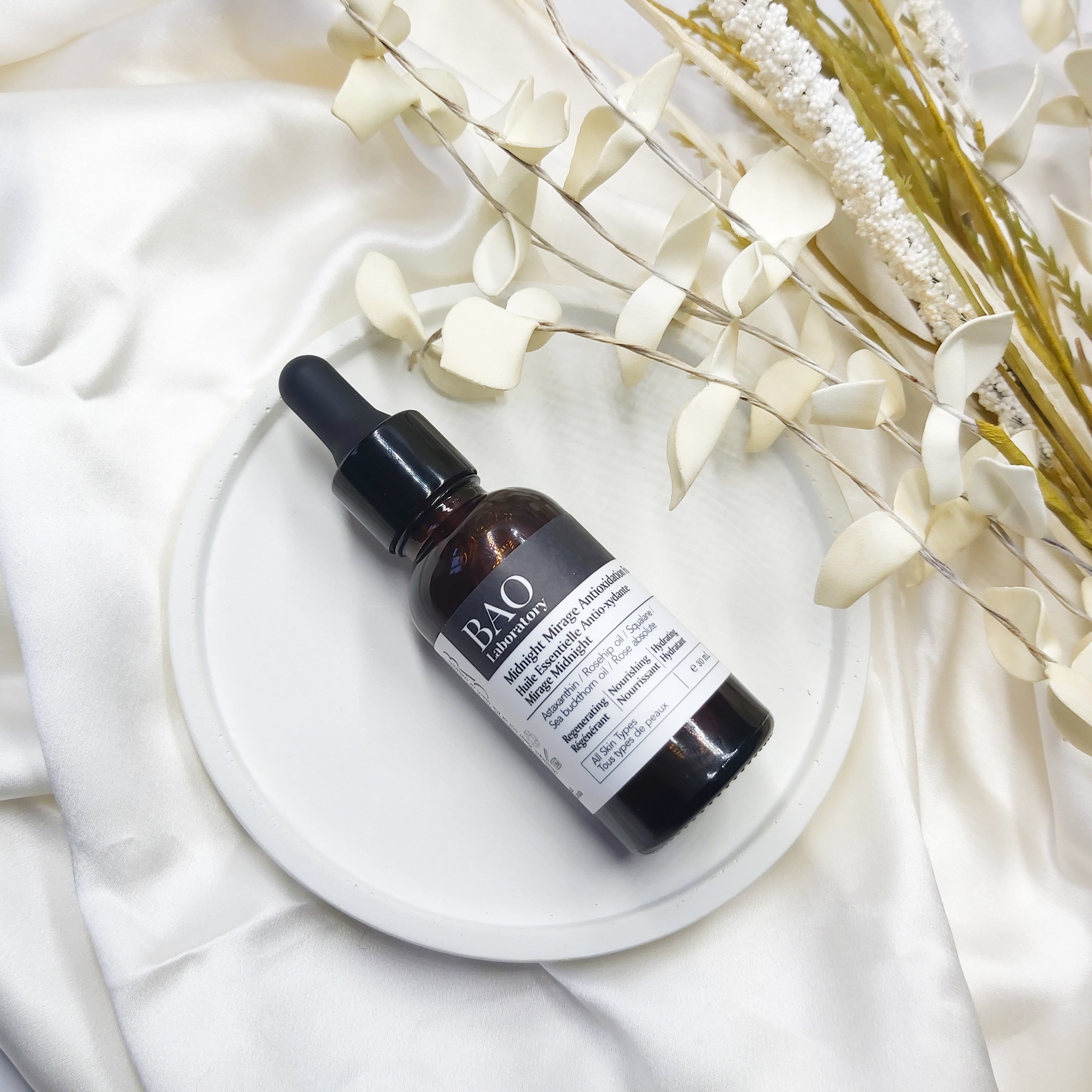 BAO Laboratory Midnight Mirage Antioxidation Facial Oil bottle on a white circular concrete dish with natural, dried affect foliage in the background - natural beauty review by Beauty Folio - Cert Clean Judge 2022
