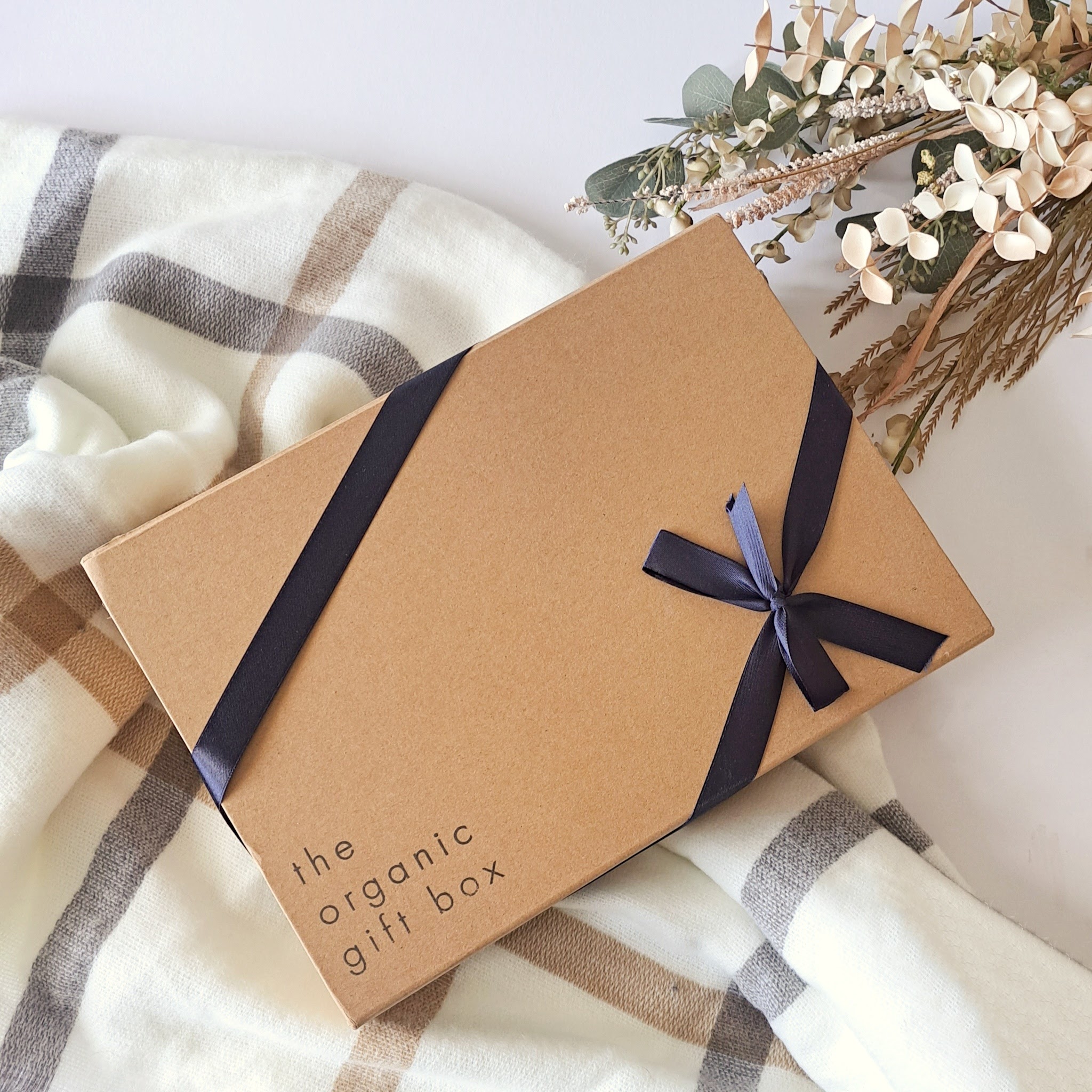 The Organic Gift Box in a branded kraft box with navy ribbon bow. Review by Beauty Folio