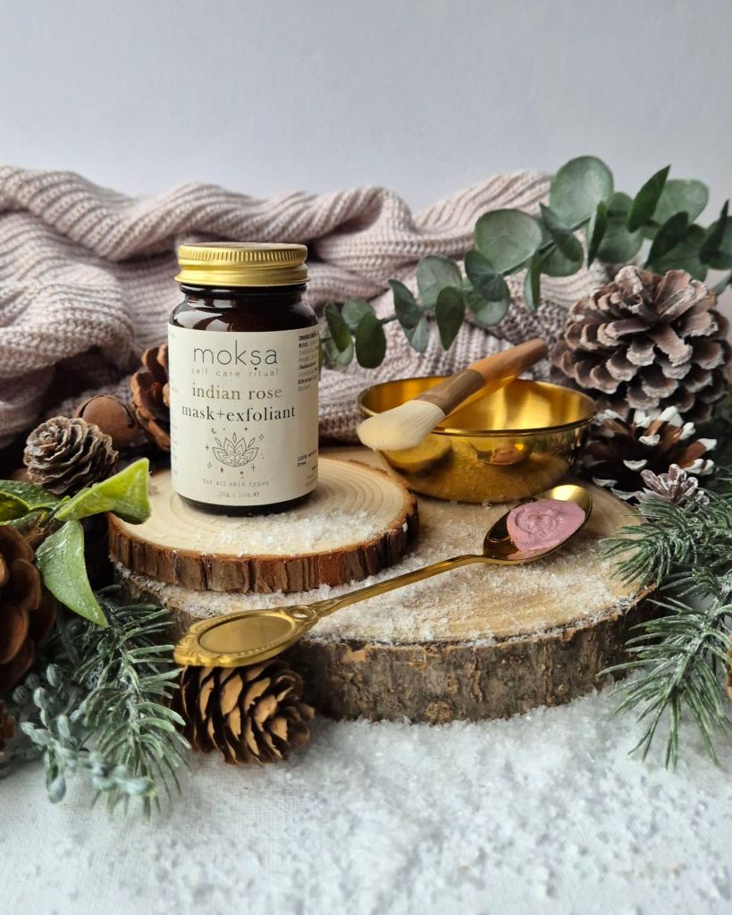 Moksa Indian Rose Mask + Exfoliant Gift Box on a log slice with foliage and artificial snow - Photo by Beauty Folio, Green Beauty Content Creator