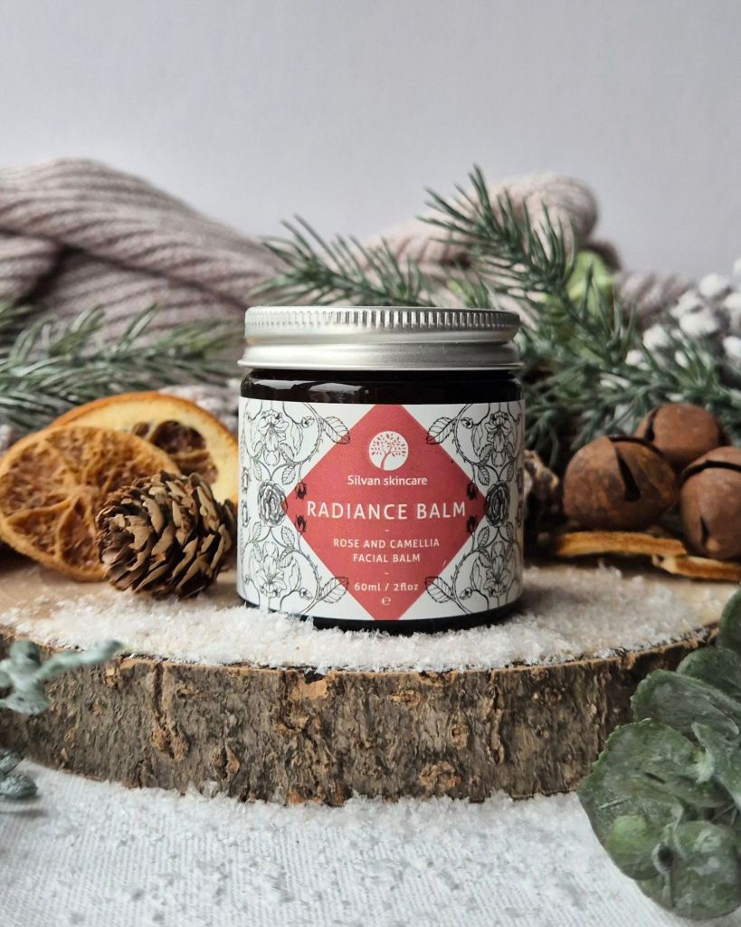 Silvan Skincare Radiance Balm on a log slice with foliage and artificial snow - Photo by Beauty Folio, Green Beauty Content Creator