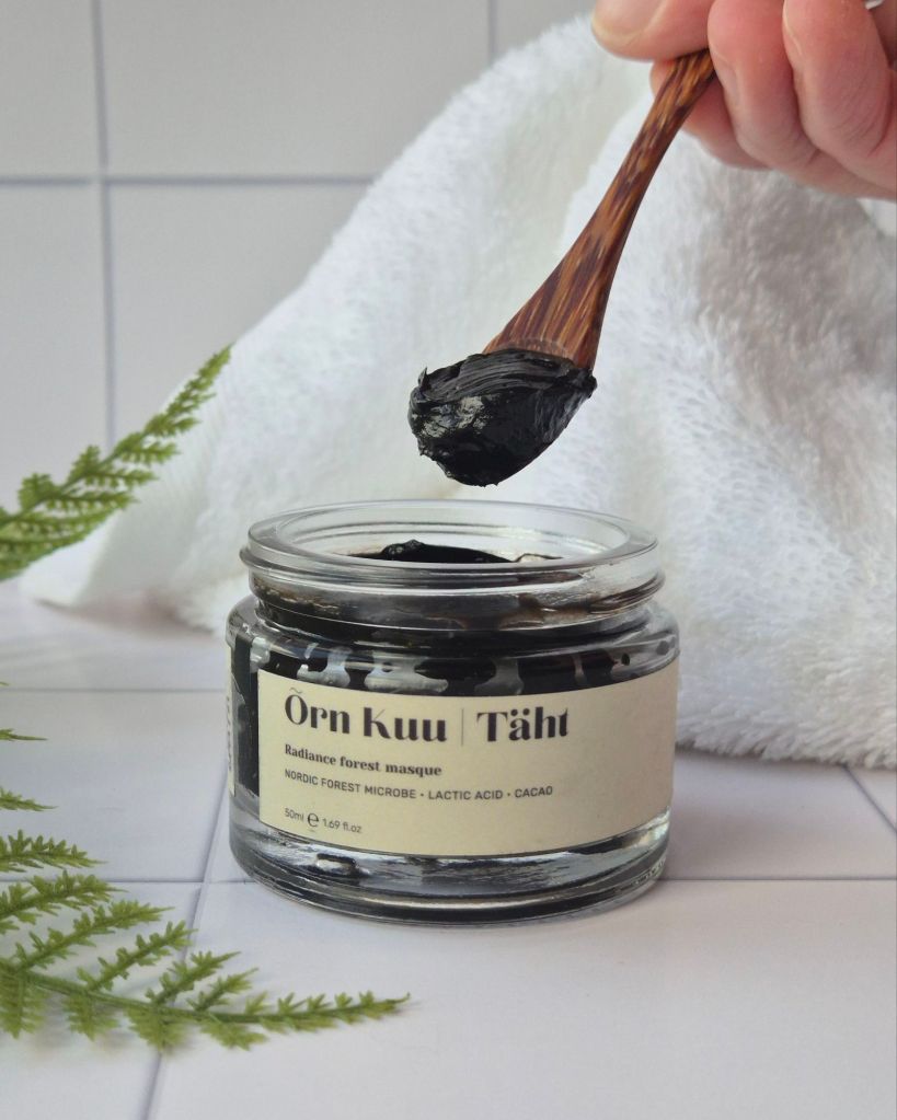Õrn Kuu's Täht Radiance Forest Masque jar on white tiles with no lid, and a spoon coming out of the jar with a little product on it - review by Beauty Folio